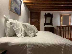 a bedroom with a white bed with white pillows at Traditional apartment in the heart of Mykonos! in Mikonos