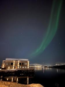 um edifício com a aurora no céu sobre a água em Steam Pier em Kvaløya