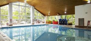 a large swimming pool in a building with a large window at The Luxurious Langdale 6 Lodge at Park Dean White Cross Bay, Lake Windermere in Windermere