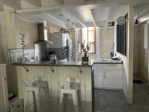 a kitchen with a counter and stools in a room at Charmante échoppe avec piscine Comme un air de campagne en ville in Bordeaux