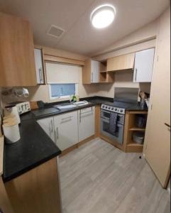 a kitchen with white cabinets and black counter tops at 51 Oaklands thorness bay Parkdean holiday resort in Cowes