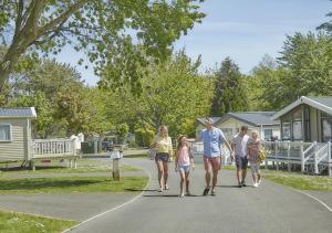 a family walking down a driveway in front of homes at 51 Oaklands thorness bay Parkdean holiday resort in Cowes