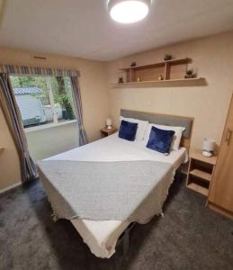 1 dormitorio con 1 cama grande con almohadas azules en 51 Oaklands thorness bay Parkdean holiday resort en Cowes