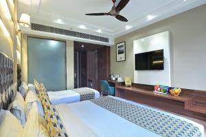 a bedroom with two beds and a desk and a television at Hotel Oak Plaza, New Delhi in New Delhi