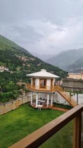 ein Haus mit einem Balkon mit grünem Rasen in der Unterkunft The Swat House in Swat