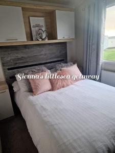 una camera da letto con letto, cuscini e finestra di Sienna's littlesea getaway a Wyke Regis