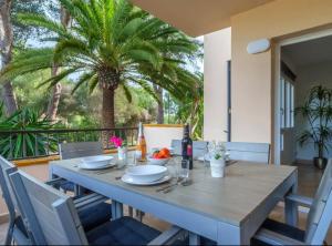 a wooden table with chairs and a palm tree at Apartamentos Los Pinos in Cala Murada