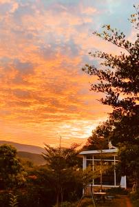 einen Sonnenuntergang über einem Haus mit Bäumen und einem Himmel in der Unterkunft Nacasoo hill in Tiên Hai