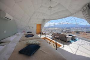 two beds in a room with a large window at Glamping Dome YOSHIMURA in Fujikawaguchiko