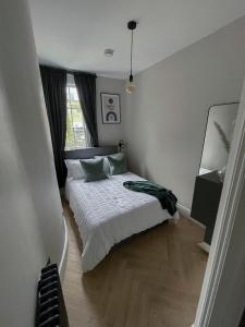 a bedroom with a bed with white sheets and green pillows at Broad Street Apartments - Central Bath in Bath