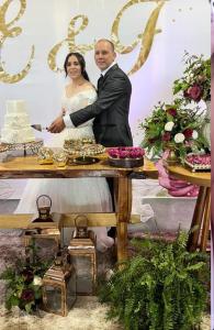 a bride and groom cutting their wedding cake at POUSADA FAZENDA PAIM in São José dos Ausentes