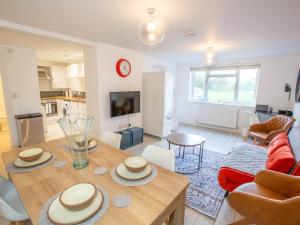 a living room with a wooden table and a kitchen at Pass the Keys Stylish apartment in peaceful Oxfordshire suburb in Kidlington