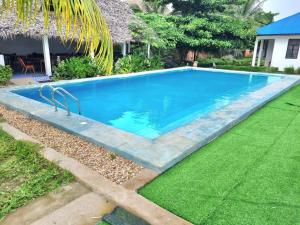 una piscina en un patio con césped verde en Kigwedeni Villas en Nungwi