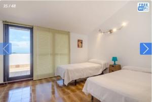 a room with two beds and a large window at Casa Mendi en Lloret de Mar in Lloret de Mar