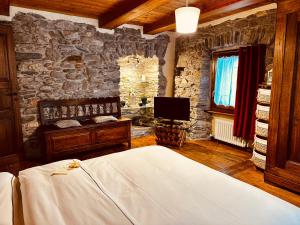 Dormitorio con pared de piedra, cama y TV en Maison Bovet, en La Salle