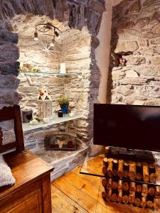 a living room with a stone wall with a fireplace at Maison Bovet in La Salle