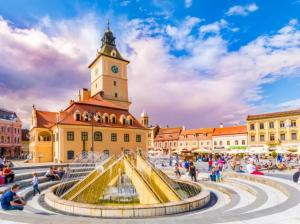 una fontana di fronte a un edificio con torre dell'orologio di Luxury Apartment a Braşov