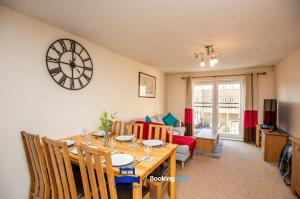 a dining room with a table and a clock on the wall at Two Bedroom Apartment By Beds Away Short Lets & Serviced Accommodation Close to Kidlington Airport and Blenheim Palace in Kidlington