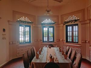 una mesa larga en una habitación con sillas y ventanas en Grand Colonial Viveka en Kurunegala