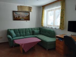 salon z zieloną kanapą i stołem w obiekcie Apartments Grabler w mieście Altmünster