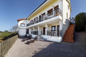 a white house with two chairs and a balcony at El Mirador de Trasvia Comillas in Trasvia