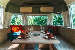 a table in the back of a train with wine glasses at Glamping aan de Maas in Kessel