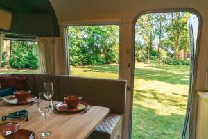 a table with wine glasses on it with a view of a yard at Amerikaanse Airstream caravan met hottub in Kessel