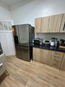 La cuisine est équipée d'un réfrigérateur en acier inoxydable et de placards en bois. dans l'établissement Appartement 2 chambre luxueuse à jette, à Bruxelles
