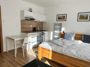 a bedroom with a bed and a desk and a kitchen at Apartman pri vleku in Telgárt