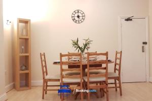 a dining room table with chairs and a clock on the wall at Spacious 5 Bedroom Apartment Ideal for Contractors By Beds Away Short Lets & Serviced Accommodation Oxford with Parking in Iffley in Oxford