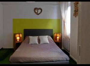 a bedroom with a green wall with a bed and two lights at Côté mer in Marseille