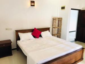 a bedroom with a large bed with two red pillows at Villa Ocean Breeze in Ahangama