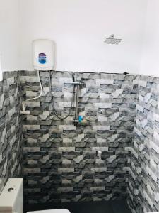 a bathroom with a stone wall with a shower at Villa Ocean Breeze in Ahangama