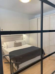 a bedroom with a bed and a glass wall at Soho Moraleja III in Alcobendas