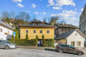 a yellow house with two cars parked in front of it at Apartmány na Trojici - DOLNÝ apartmán in Banská Štiavnica
