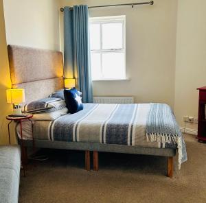 1 dormitorio con 1 cama con cortina azul y ventana en The Waterside B&B, en Westport