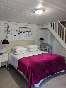 sypialnia z dużym łóżkiem i fioletowym kocem w obiekcie Clos du Gaja près de Jazz in Marciac w mieście Troncens