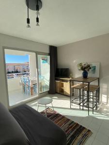 Una sala de estar con un sofá, una mesa y sillas. en Appart à 200m de la plage, en Sète