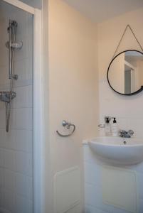 a white bathroom with a sink and a mirror at Spacious 2 bed apartment in Canterbury