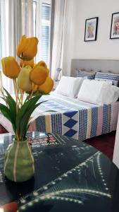 um vaso com flores amarelas numa mesa num quarto em Apartamento Burgo " A Preferida " no Funchal