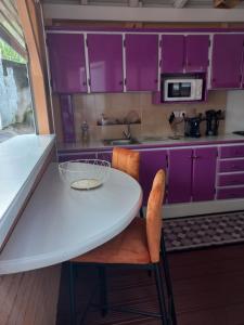 a kitchen with purple cabinets and a white table and chairs at Joli appartement in Rivière-Pilote