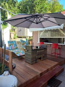 a patio with an umbrella and chairs on a deck at Joli appartement in Rivière-Pilote