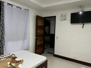 a room with a bed and a television and a door at Jancas Vacation Home Camiguin Family Room in Catarman