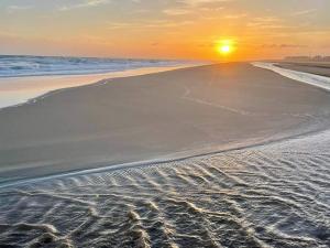 a beach with the sun setting on the horizon at Sol y Luz in Isla del Moral