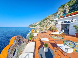 a deck with chairs and tables and the water at Villa Costa degli Dei in Furore