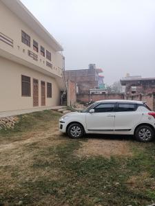 biały samochód zaparkowany przed budynkiem w obiekcie ARJUN PAYING GUEST HOUSE w mieście Ayodhya