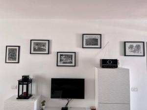 a living room with a television and pictures on the wall at Casa Sol Azul in Puerto Calero