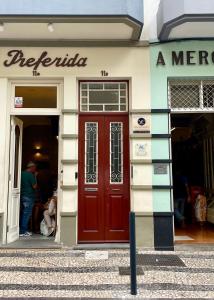a store front with a red door and a man standing outside at Apartamento Burgo " A Preferida " in Funchal