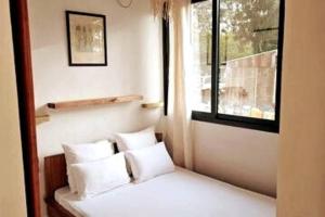 a bedroom with a bed with white pillows and a window at Bungalow Ramena beach Antsiranana in Andjamen