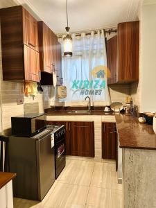 a kitchen with wooden cabinets and a stainless steel refrigerator at Kiriza Homes in Bulindo